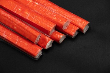Crab sticks on a black background with space for text laid out in a row
