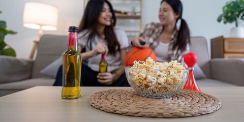 LGBT couple relaxing at home with basketball snacks and drinks, enjoying each other's company