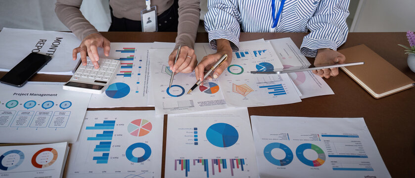 Business team analyzing project management charts and data in a modern office meeting - Powered by Adobe