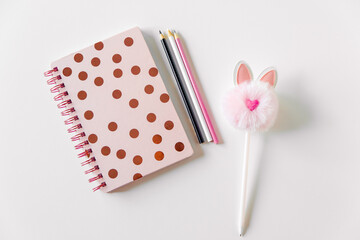 Stylish flat lay, beautiful women's notebook in polka dots, cute fluffy pen and pencils. feminine background, copy space
