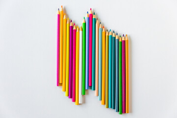Obraz premium Multicolor pencils on a white background, flat lay. Rainbow pastel bright colors. Creativity,art and art, childhood, drawing and design concept
