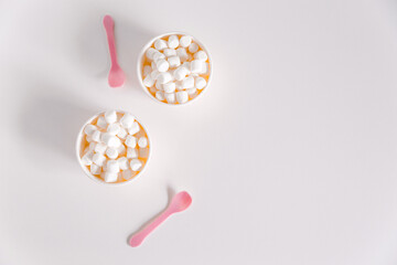 Minimalist white background with marshmallow boxes and cute pink spoons. Mockup for design, lots of free space, flat lay