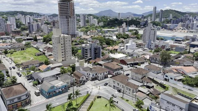 Drone flies over church on hill overlooking Vila Nova neighborhood and flies over Ramiro Ruediger Park on sunny day in Blumenau, Santa Catarina, Brazil