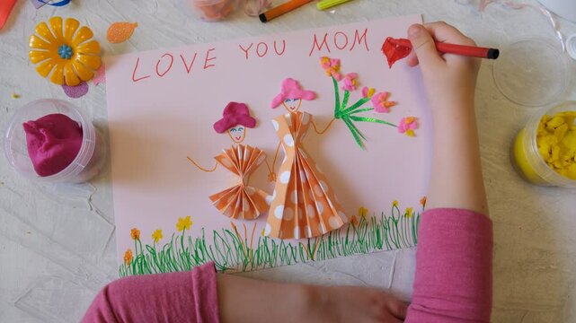 Child making homemade greeting card from paper and clay, plasticine as gift for Mothers day, Birthday or Valentines day . Arts  crafts concept.