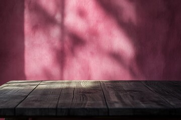Rustic wooden table against a pink wall with leaf shadows.