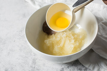Overhead view of raw egg, whole raw egg in a white measuring cup