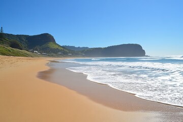 Serene Coastal Landscape with Golden Sand and Gentle Waves Under Clear Blue Sky, Showcasing Nature's Beauty and Tranquility in a Seaside Setting