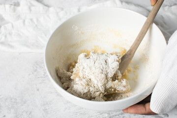 mixing flour into vanilla cookie dough in a white mixing bowl, plain vanilla cookie dough about to...