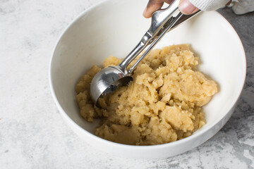 scooping vanilla cookie dough in a white mixing bowl, plain vanilla cookie dough about to be baked, process of making vanilla cookie dough