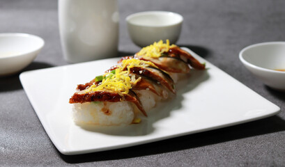 Eel sushi with egg garnish on top. A close-up shot of fresh seafood dishes.
