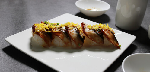 Eel sushi with egg garnish on top. A close-up shot of fresh seafood dishes.
