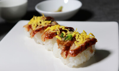 Eel sushi with egg garnish on top. A close-up shot of fresh seafood dishes.
