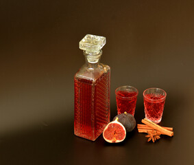 Fig liqueur with cinnamon and anise in a crystal decanter and two frames on a black background.