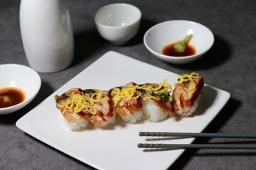 Eel sushi with egg garnish on top. A close-up shot of fresh seafood dishes.
