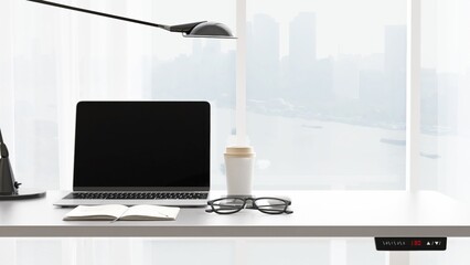 Desktop of modern gray stand up desk with computer laptop, notebook, eyeglasses in sunlight from...