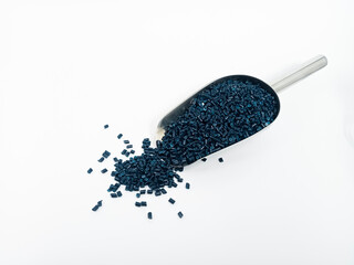 Dark blue masterbatch, polymer granules carrying pigment inside stainless steel scope, isolated on...