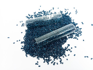 Dark blue masterbatch plastic granules in glass tube, polymer carries pigment poured in white...