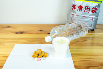 ビニール袋でカバーされた水が入った紙コップと避難所配給品の一食分の乾パン