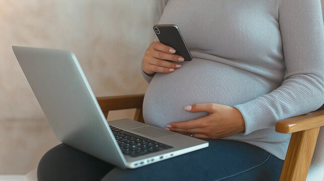 Pregnant woman using laptop and smartphone while working from home
