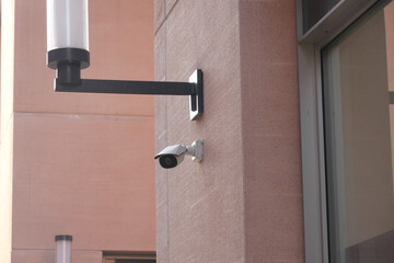 A visibly damaged security camera is mounted on a wall with its bracket still attached