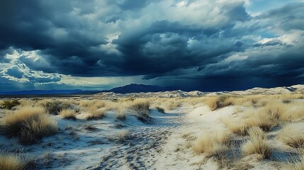 Dramatic storm clouds over a desert landscape with sand dunes and sparse vegetation.