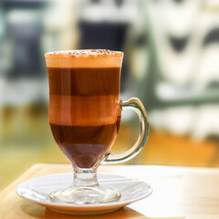 Delicious mochaccino coffee served in elegant glass cup on table in cafe