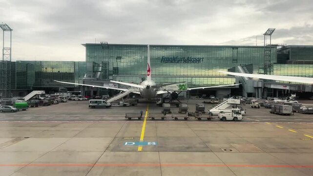 Luggage train vehicle drive on airport with airplane docked at Frankfurt Airport with bustling activity