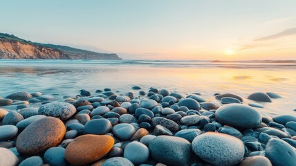 weathered rocky coastlines Pebbles on a beach with sunset over the ocean waves.