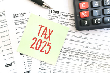 Text Tax 2025 on the note paper with calculator and taxes documents. Business and Annual tax...
