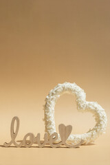 Wooden word LOVE White lilac flowers heart shaped in pastel backdrop. Symbol of love floral arrangement. Spring concept idea Valentine's Day, weeding proposal postcard copy space for your text 