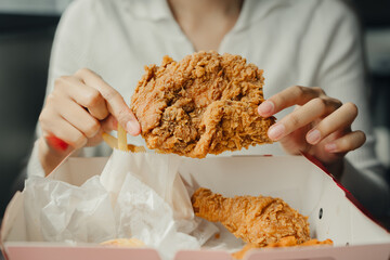 Crispy fried chicken being held by person, served in takeout box