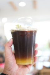 Yuzu Americano on man hand with blur background. Close up