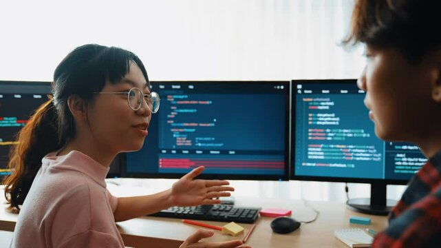 Slow motion back end software developer engineer for computer programming working together on debugging writing computing code, solving complex algorithms display on monitor in office. Burgeoning