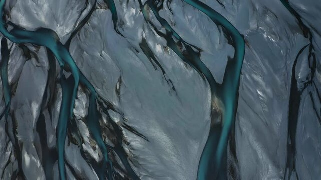 Top down drone shot of Blue Glacial Braided River delta weaving through vast gray valley, Tasman River, New Zealand, South Island