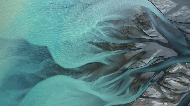 Top down drone shot of Gorgeous Glacial Blue Braided Tasman River flowing into Lake Pukaki like abstract art, New Zealand