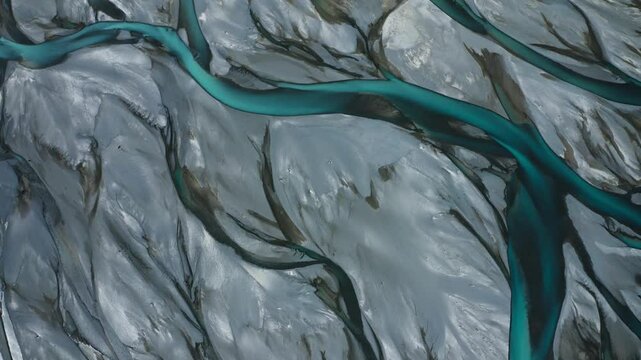 Top down drone shot of Blue Glacial Braided River veins and streams weave and flow through grey landscape, New Zealand