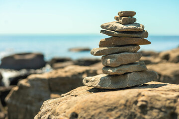 Stone tower at sunny sea coast beach balance harmony zen symbol. Natural pebble pyramid