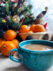 Decorative teal cup with coffee beside fresh oranges and a basket during winter morning light. Christmas and New Year
