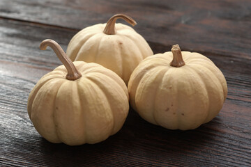 Whole uncooked decorative pumpkins in a row on a white dish with a wooden background. Autumn decoration