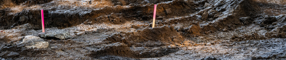 Residential re-development, old house taken down and lot ready for new construction, surveyor stakes and piles of dirt, frosty frozen ground in winter
