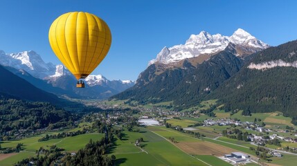 Fototapeta premium Winter Activities, A vibrant yellow hot air balloon floats above a picturesque green valley surrounded by majestic mountains under a clear blue sky.
