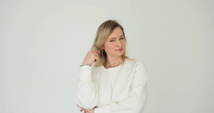 Charming thoughtful smiling woman twirling lock of hair on white background