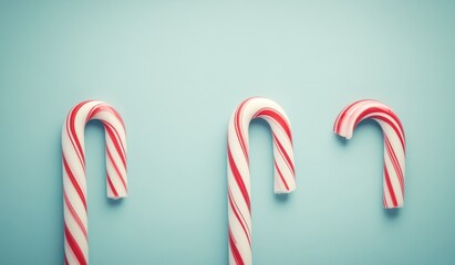 Three red and white candy canes on a light blue background.