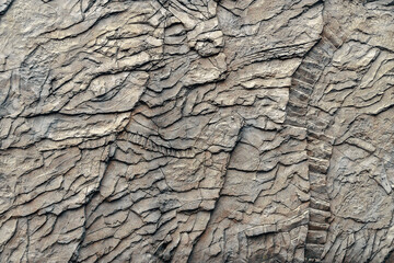 The background of the photo with the texture of a stone wall. The texture of a wall covered with weathering and cracks. Background with natural stone texture. Textured stone wall. 