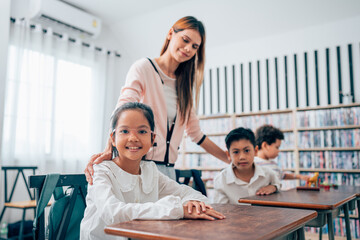 Fototapeta premium Happy school teacher and students having interesting engaging activities in class. Little children sitting around classroom table, talking and playing fun games together.