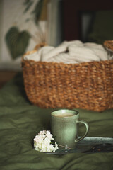 cozy summer bedroom details with green bedlinen and basket with clothes