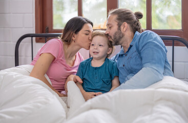 Family enjoying a cozy morning together in bed with warm blankets and natural light