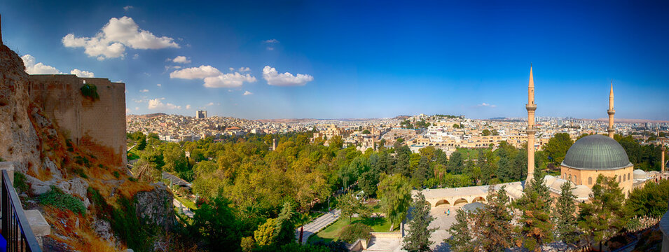 Panoramic view old town city Urfa (Sanliurfa) as view from castle,Urfa,Turkey. The castle walls are  left and the Halil Ur-Rahman Mosque is right. Blue sky and clouds. Green trees and old city summer.