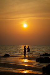 Beautiful landscape of two people on the Long Beach (Phra Ae Beach) in Koh Lanta, Thailand, at sunset. 