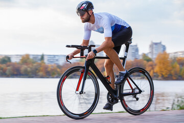 Cyclist rides along waterfront path during autumn afternoon in a city